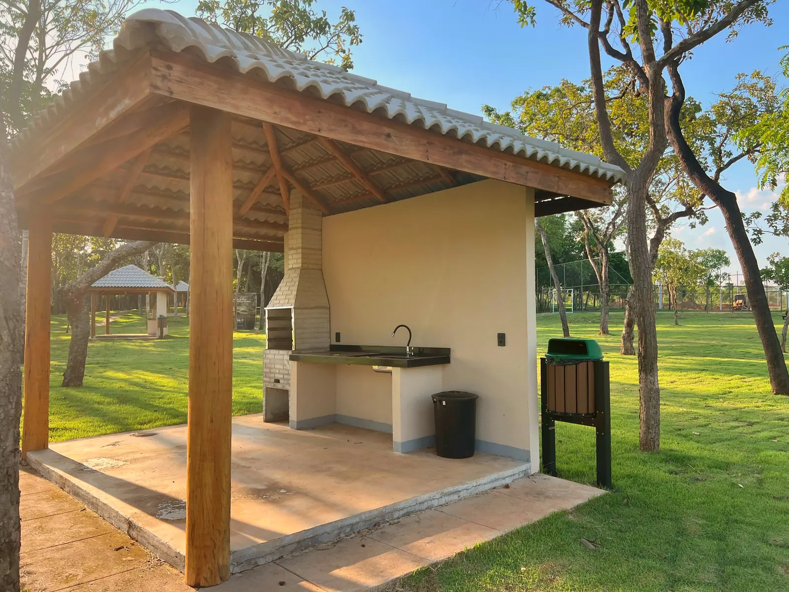 Quiosque com churrasqueira e pia do Quinta do Lago, no gramado sob as árvores